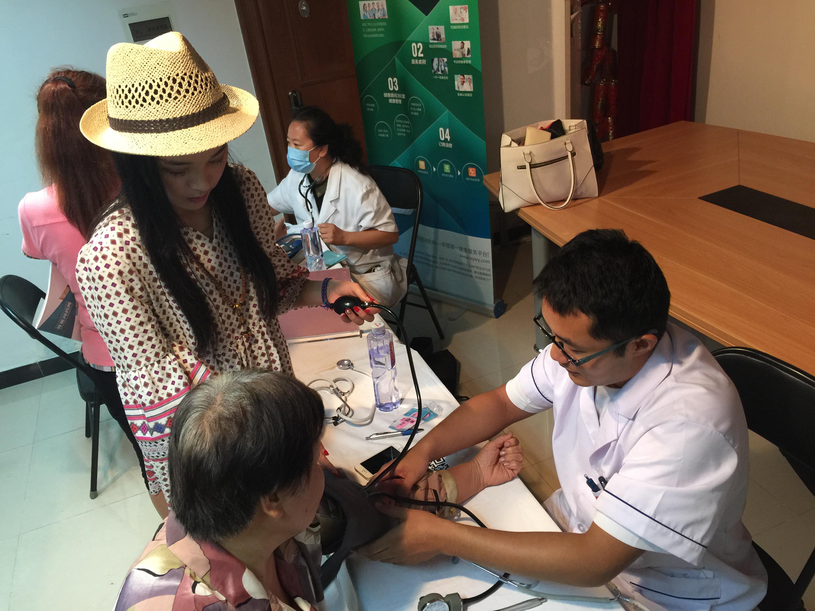 寻医问药网的工作人员辅助着医生为居民测量血压。